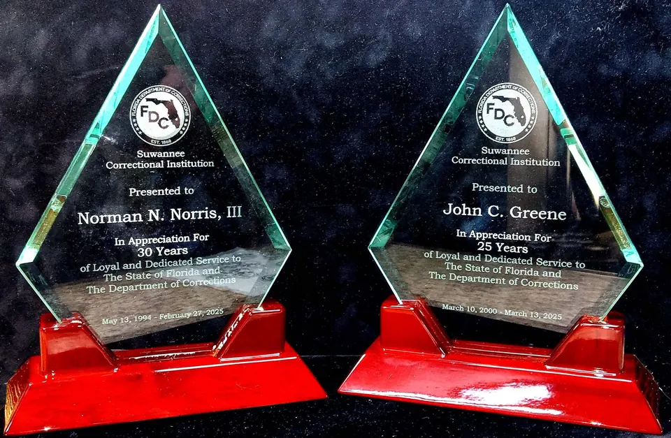 Two triangular glass service awards on red bases